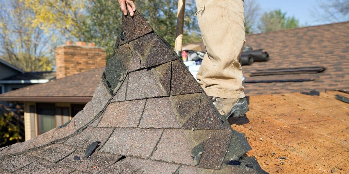 akron-roofer-holding-up-shingles-that-were-damaged-by-a-storm